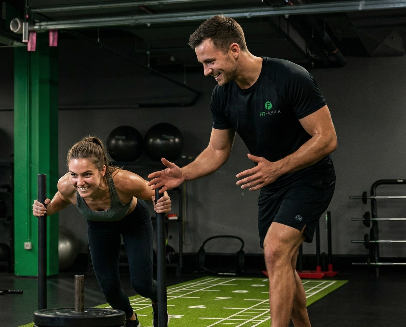 Trainer der Fit Fabrik motiviert ein Mitglied beim Schlittentraining